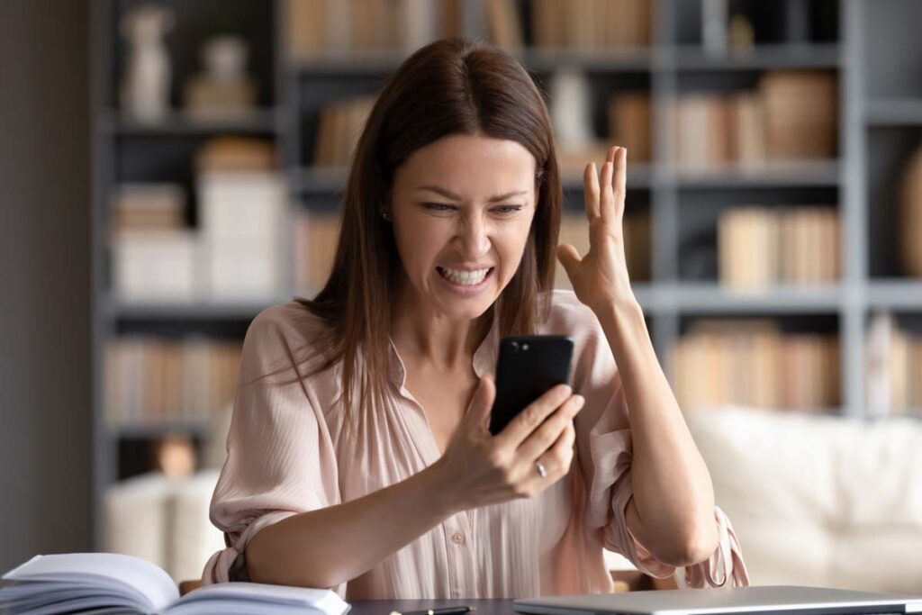 An irritated woman looking at a spam text on her phone, representing the AdaptHealth class action lawsuit settlement.