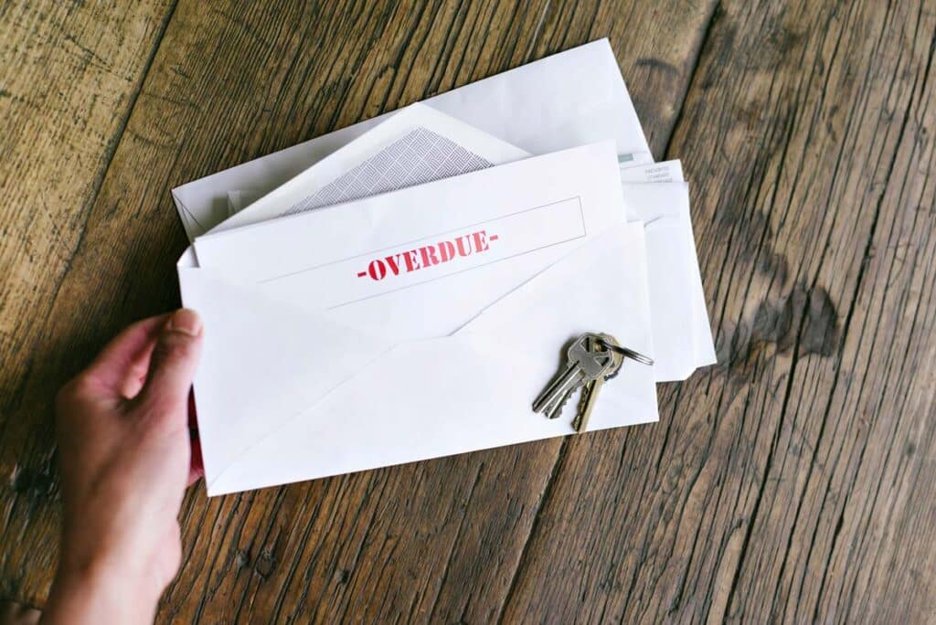 Close up of a hand holding an envelope that reads: overdue, representing the GHP Management settlement.