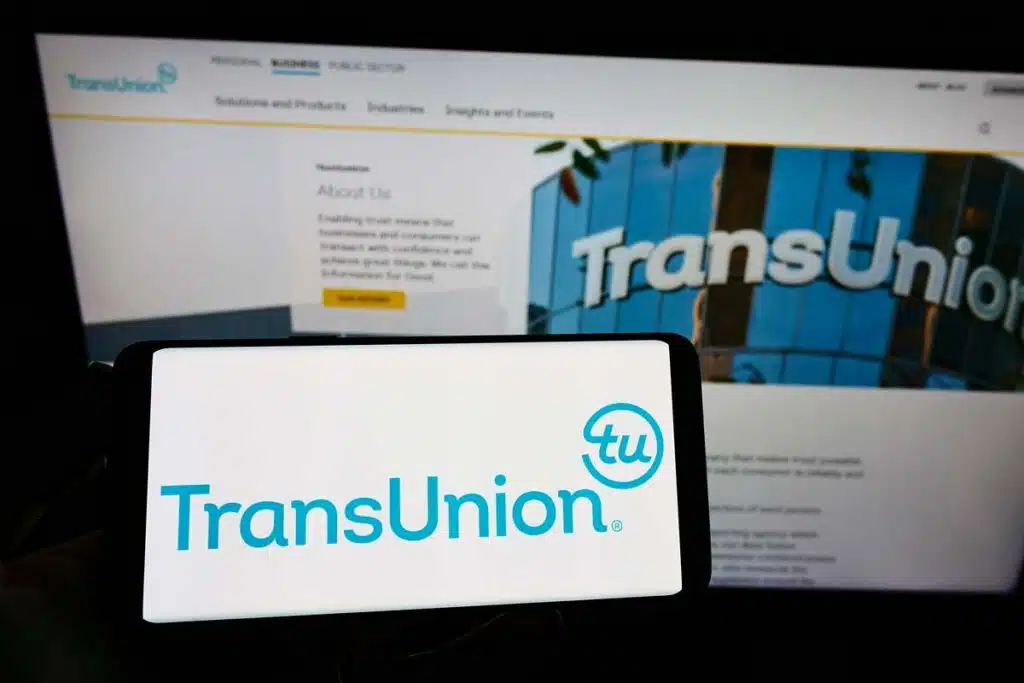TransUnion logo displayed on a smartphone screen in front of the TransUnion website, representing the TransUnion settlement.