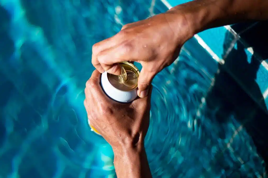 Close up of hands opening a seltzer can by the pool, representing the Vizzy seltzer class action.