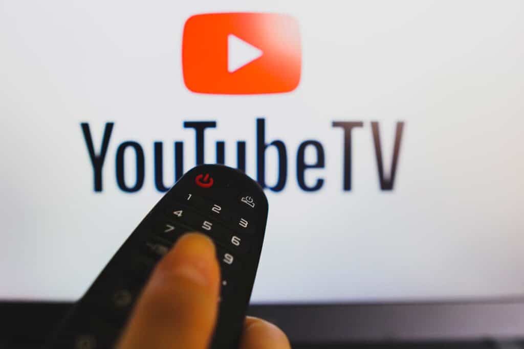 A close-up of a remote with a YoutubeTV logo displayed in the background, representing Google YouTube TV advertising.