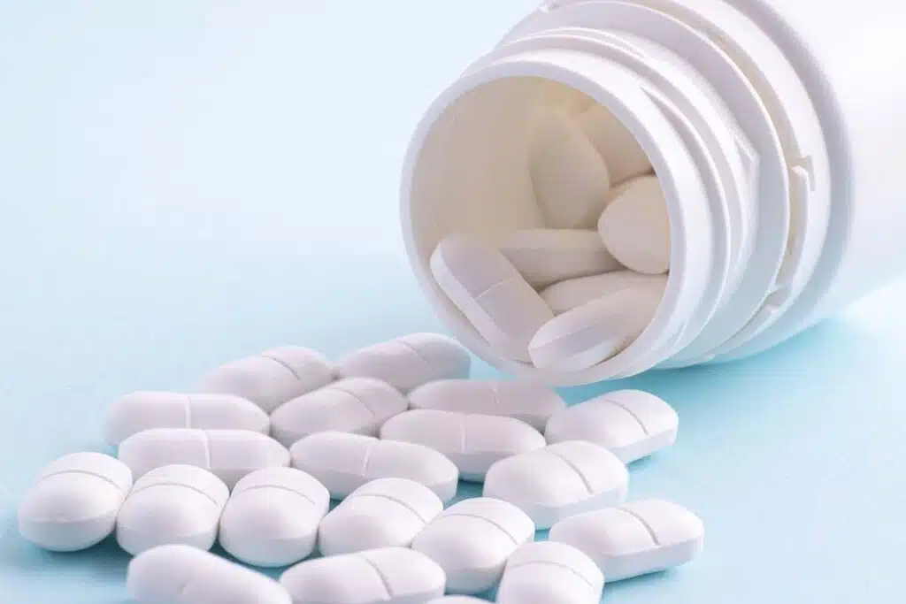 Close up of white pills spilling from a bottle, representing the Truvada, Atripla and other HIV drugs class action lawsuit settlement.
