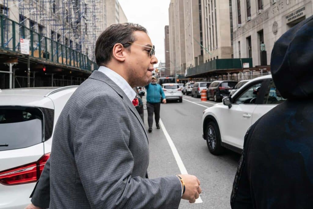 Photo of George Santos walking on a NY street, representing the Santos charges.