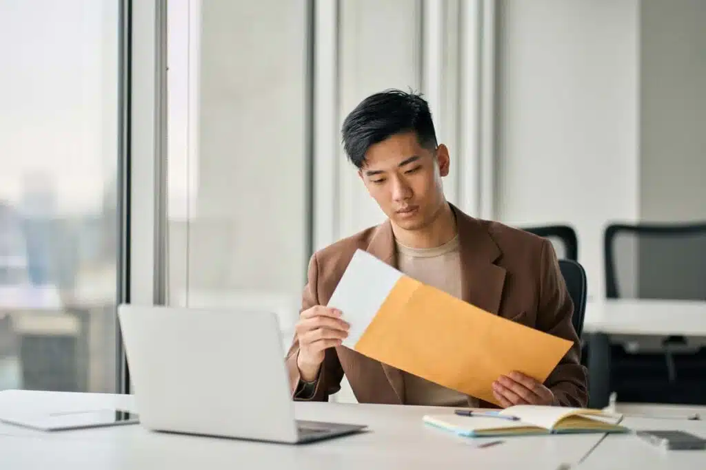 Adult male pulling a document out from an envelope, representing the Gotham settlement.