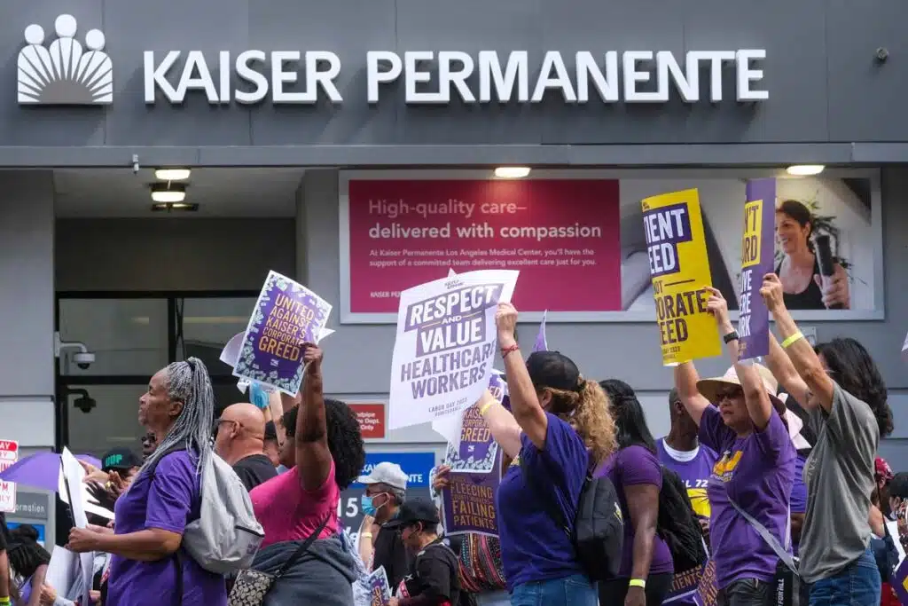 Workers on strike in front of a Kaiser Permanente building, representing the Kaiser deal.