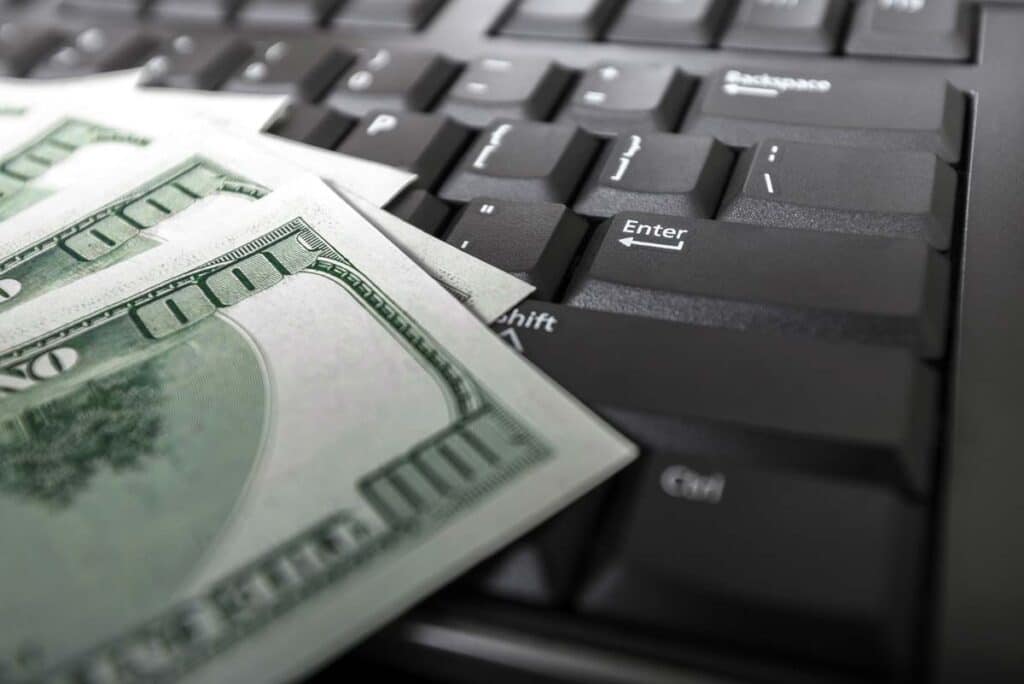 Close up of cash atop a laptop keyboard, representing the improper internet provider subsidy claims.