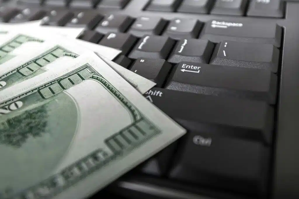 Close up of cash atop a laptop keyboard, representing the improper internet provider subsidy claims.