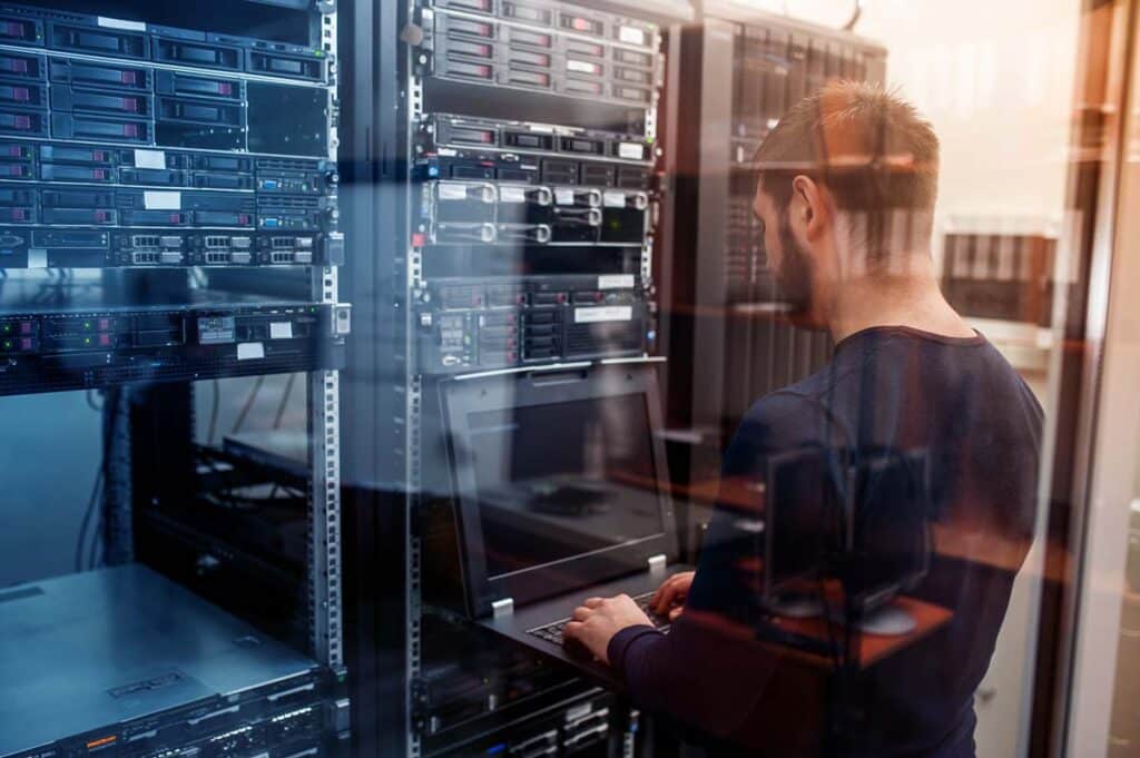 Young IT worker using a laptop in a server room, representing the Steel River Systems data breach class action settlement.