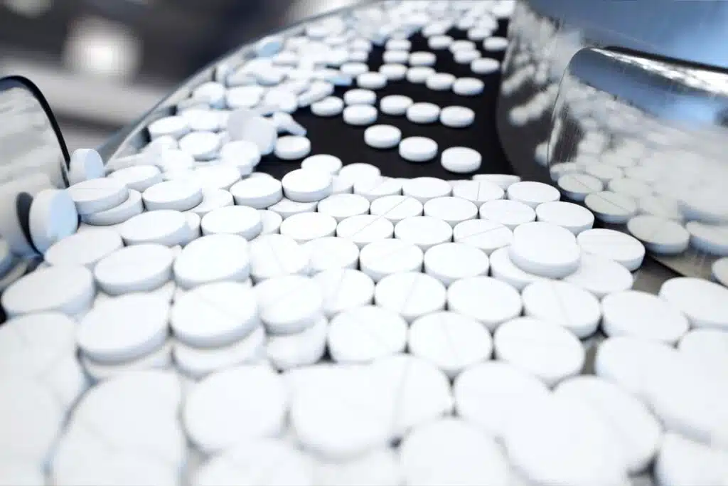 Close up of white tablet pills on a conveyor belt, representing the betaxolol recall.