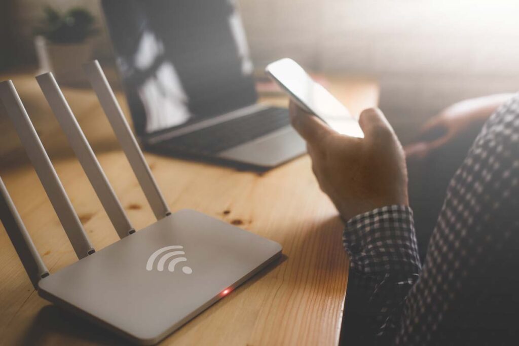 Close up of a router and a person using a smartphone, representing the FCC discrimination rule.
