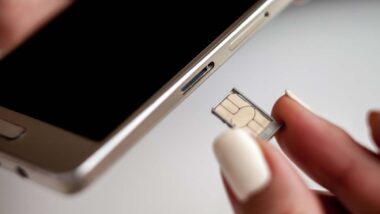 Close up of a woman putting a SIM card into her phone, representing the cell phone SIM card fraud rules.