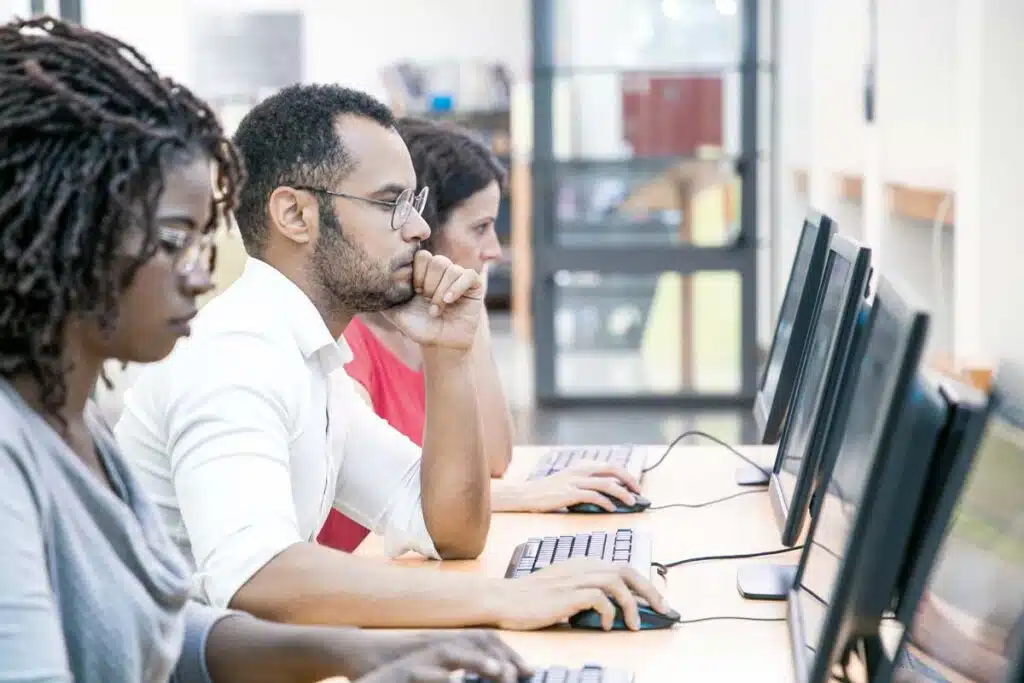 A group of test takers taking a computerized test in a testing center, representing the NABP NAPLEX test class action lawsuit settlement.