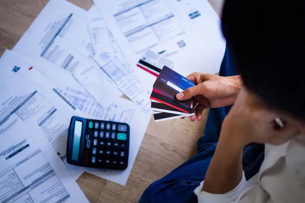 A woman looking down at her credit card bills while holding credit cards, representing credit card debt.
