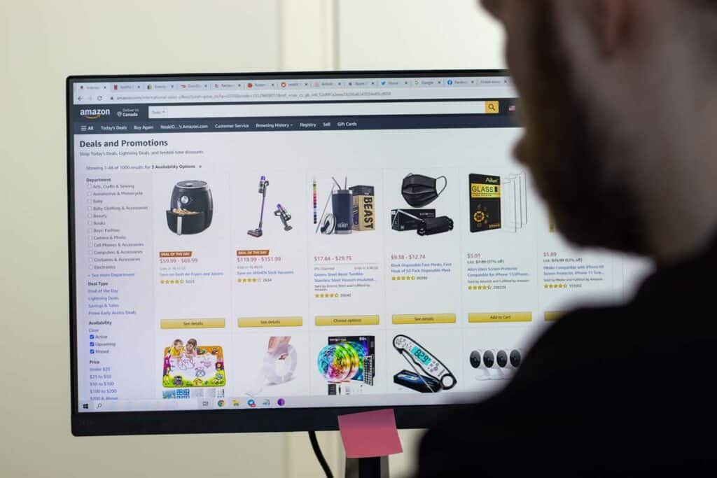 A man in front of a computer with the Amazon website displayed on the screen, representing the Amazon lawsuit.