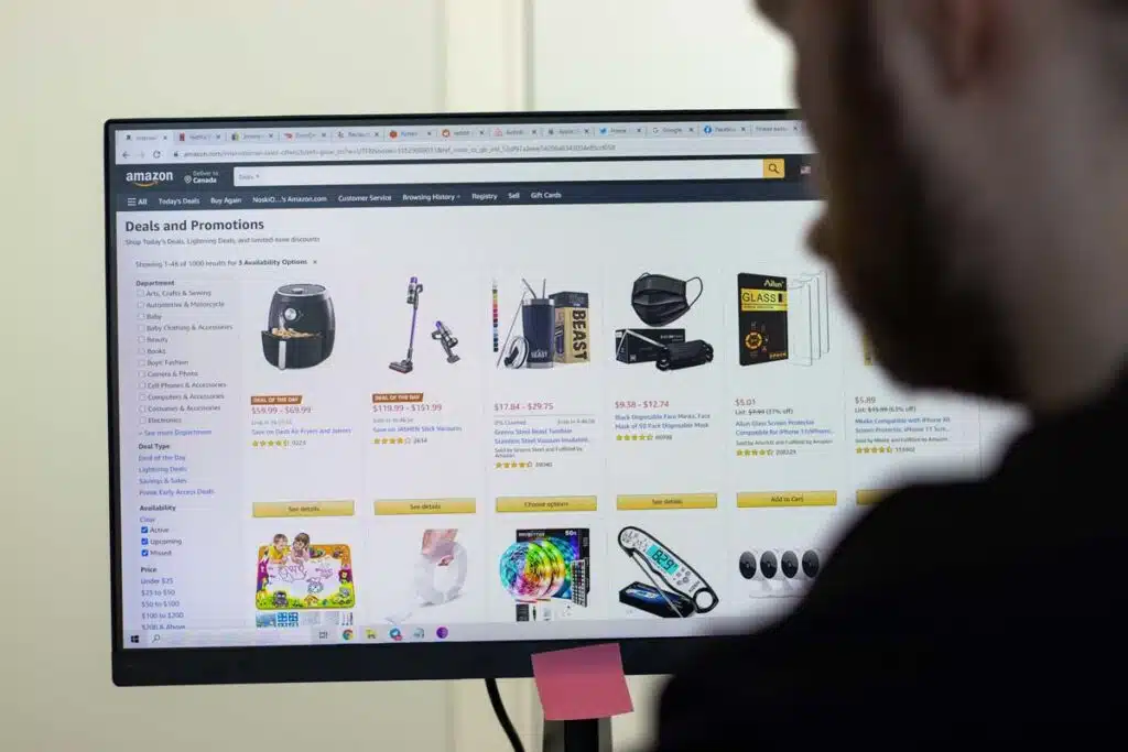 A man in front of a computer with the Amazon website displayed on the screen, representing the Amazon lawsuit.