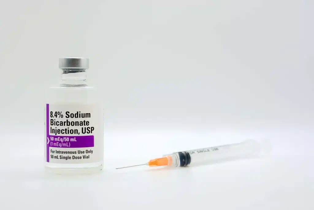 Sodium Bicarbonate vial next to a medical syringe, representing the injection recall.