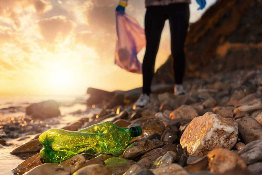 A woman picking up trash next to a river, representing the Pepsi single-use plastic lawsuit.