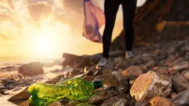 A woman picking up trash next to a river, representing the Pepsi single-use plastic lawsuit.