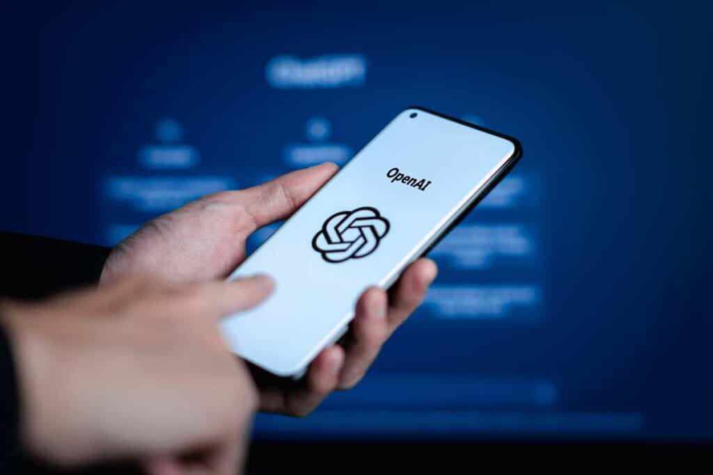 Close up of a man holding a smartphone with the Open AI logo displayed, representing the Open AI nonfiction theft class action.