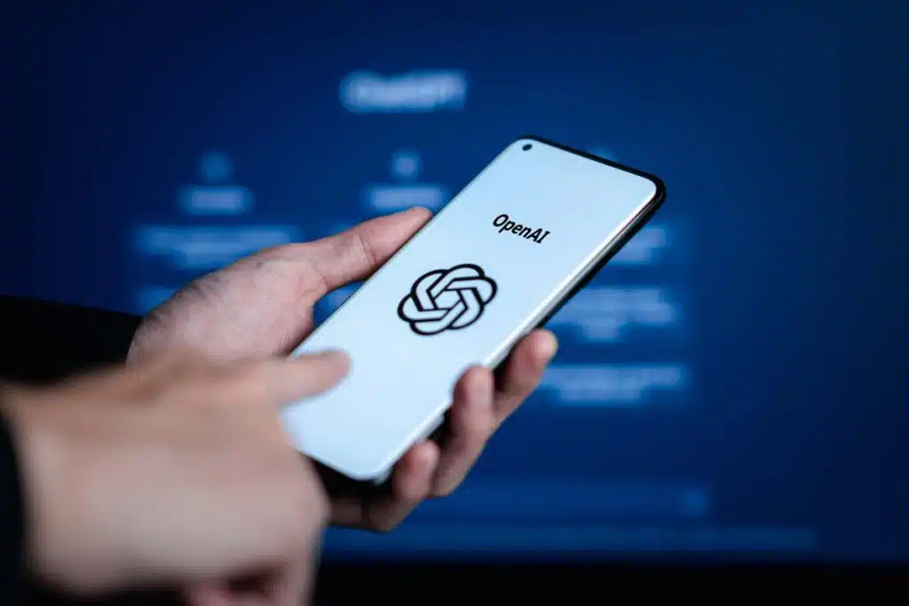 Close up of a man holding a smartphone with the Open AI logo displayed, representing the Open AI nonfiction theft class action.