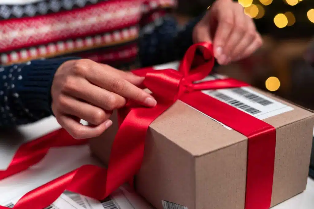 Close up of a person wrapping a bow on a shipping box, representing the holiday shipping deadlines.