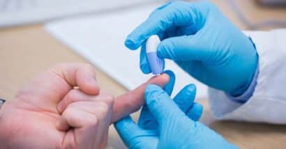 Close up of a medical professionals hands completing a finger prick blood collection, representing the Theranos class action lawsuit settlement.