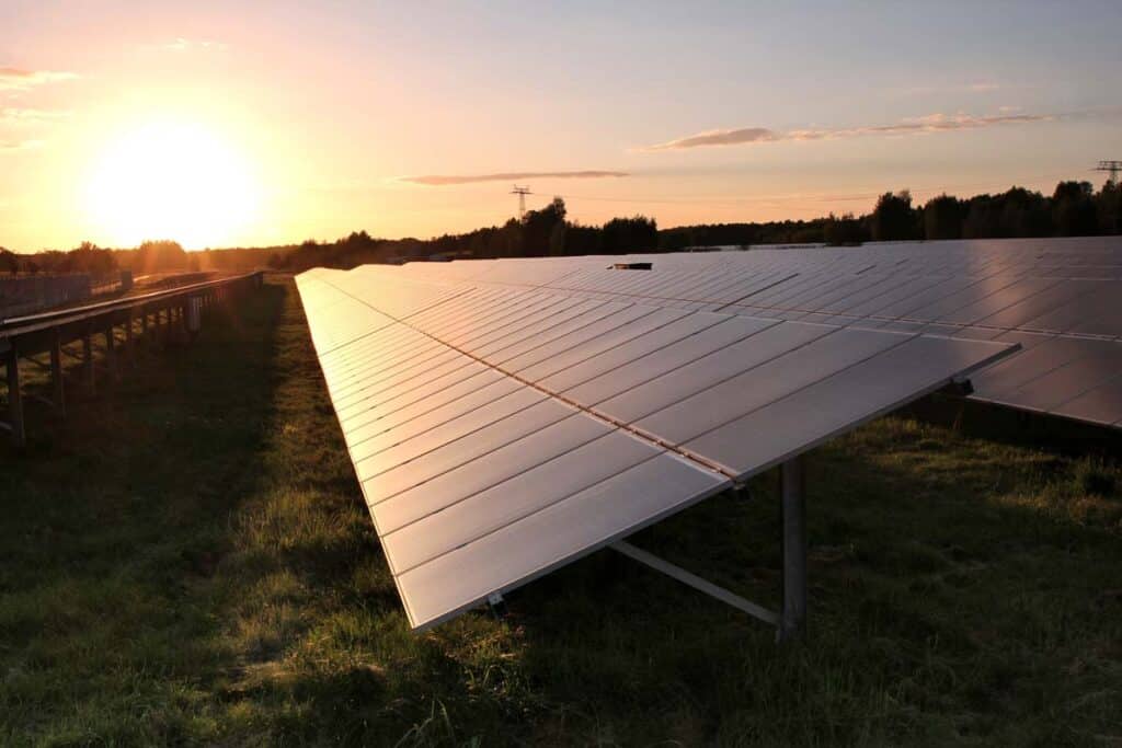 Close up of a solar panel in a field against a sunset, representing the Biden solar equipment tariffs.