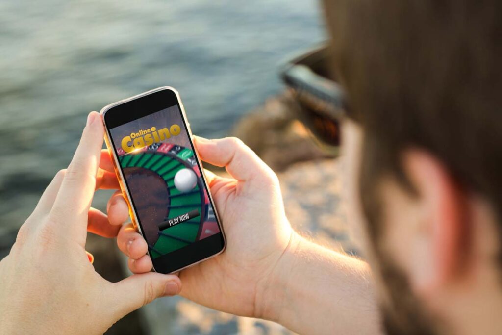 Close up of a man playing a casino game on his smartphone, representing the Amazon casino apps class action.