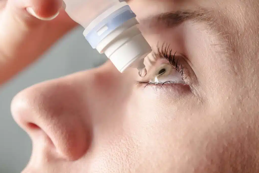 Close up of a woman putting eye drops in her eye, representing the eye drops recalls.