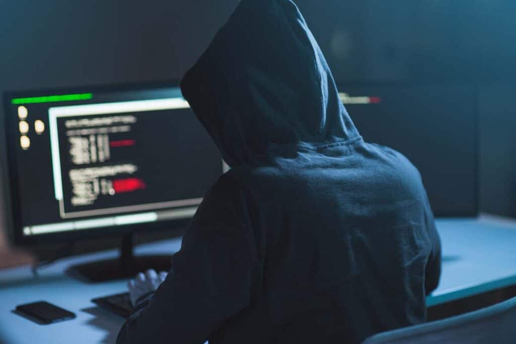 A hooded cybercriminal using a computer, representing the ZeroedIn Technologies data breach class action.