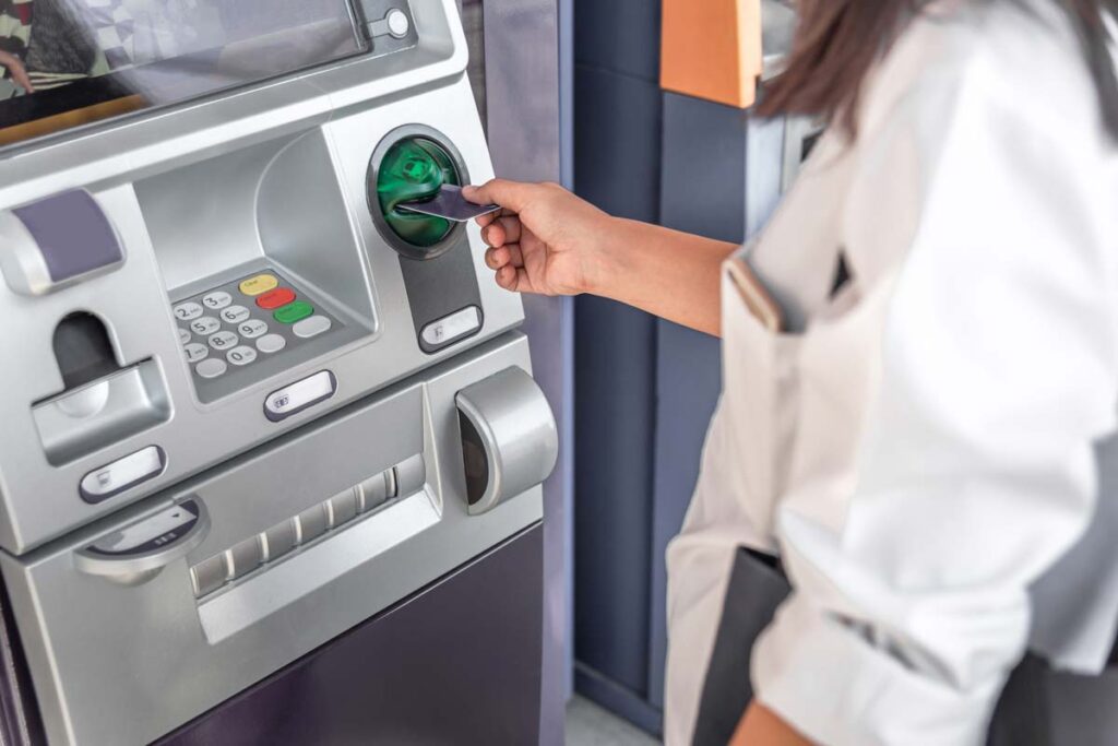 Close up of a woman putting a card into an ATM, representing recent banks class action lawsuit claims.