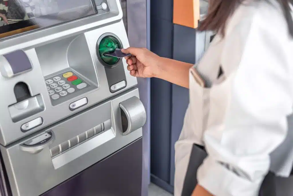 Close up of a woman putting a card into an ATM, representing recent banks class action lawsuit claims.