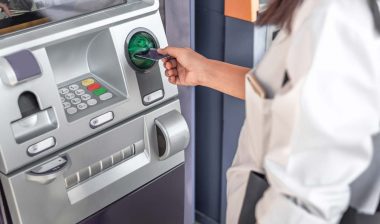 Close up of a woman putting a card into an ATM, representing recent banks class action lawsuit claims.