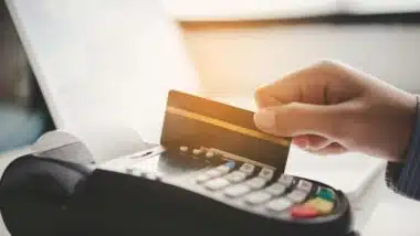 Close up of a card being swiped on a point-of-sale machine, representing the Visa and Mastercard settlement.