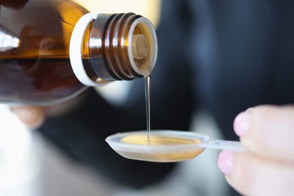 Close up of oral medicine being poured into a measuring spoon, representing the Sandimmune recall.