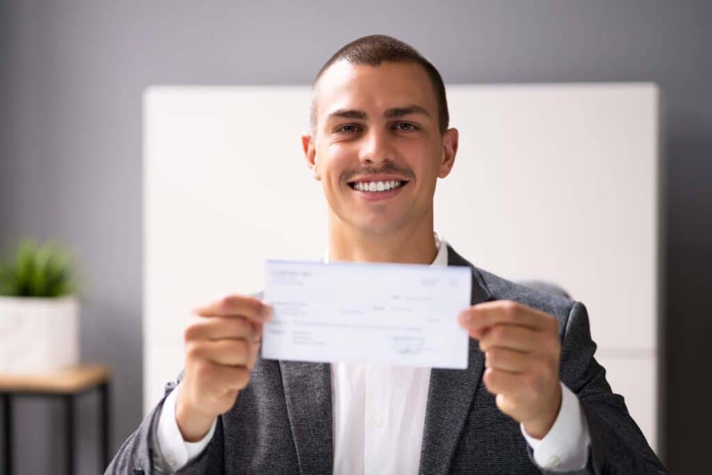 A happy man holding a check, representing the top settlements of 2023.