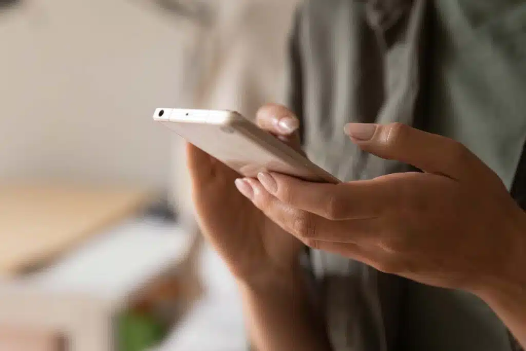 Close-up of a woman's hands texting on an Android smartphone, representing the Apple antitrust referral over the Beeper Mini block.
