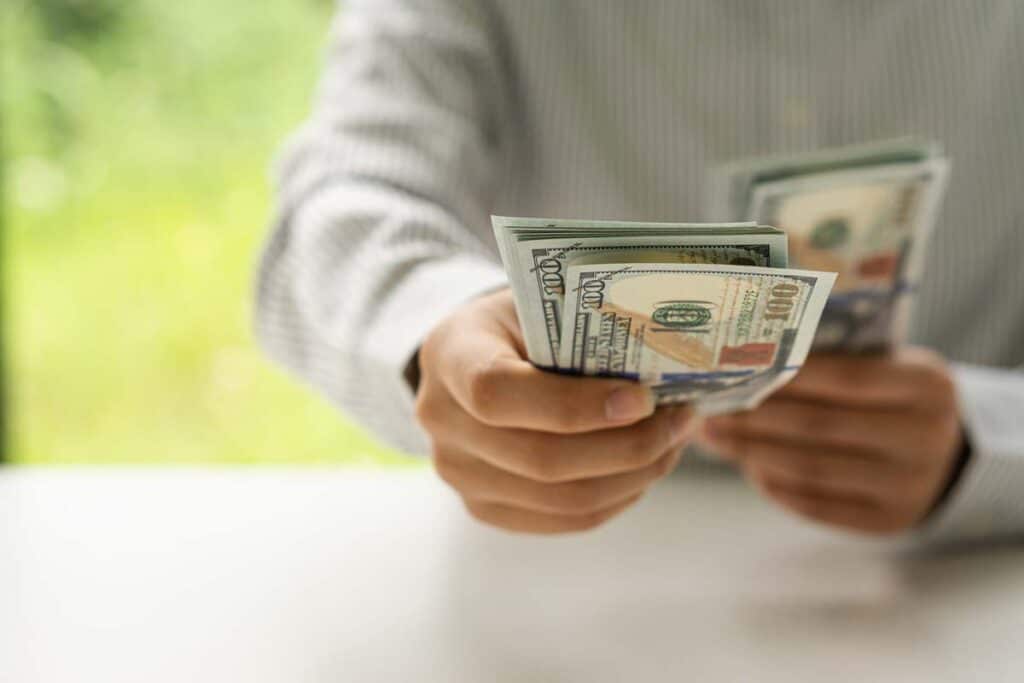 Close up of a womans hands holding cash, representing recent class action rebates.