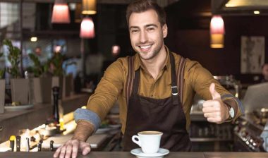 A coffee shop employee giving a thumbs up while working, representing the minimum wage raise.