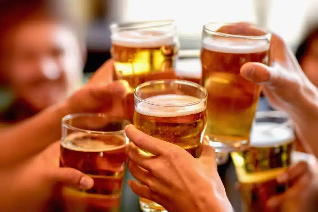 Close up of a group of friends holding glasses of beer, representing U.S. beer consumption.
