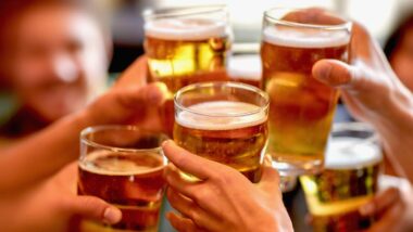 Close up of a group of friends holding glasses of beer, representing U.S. beer consumption.