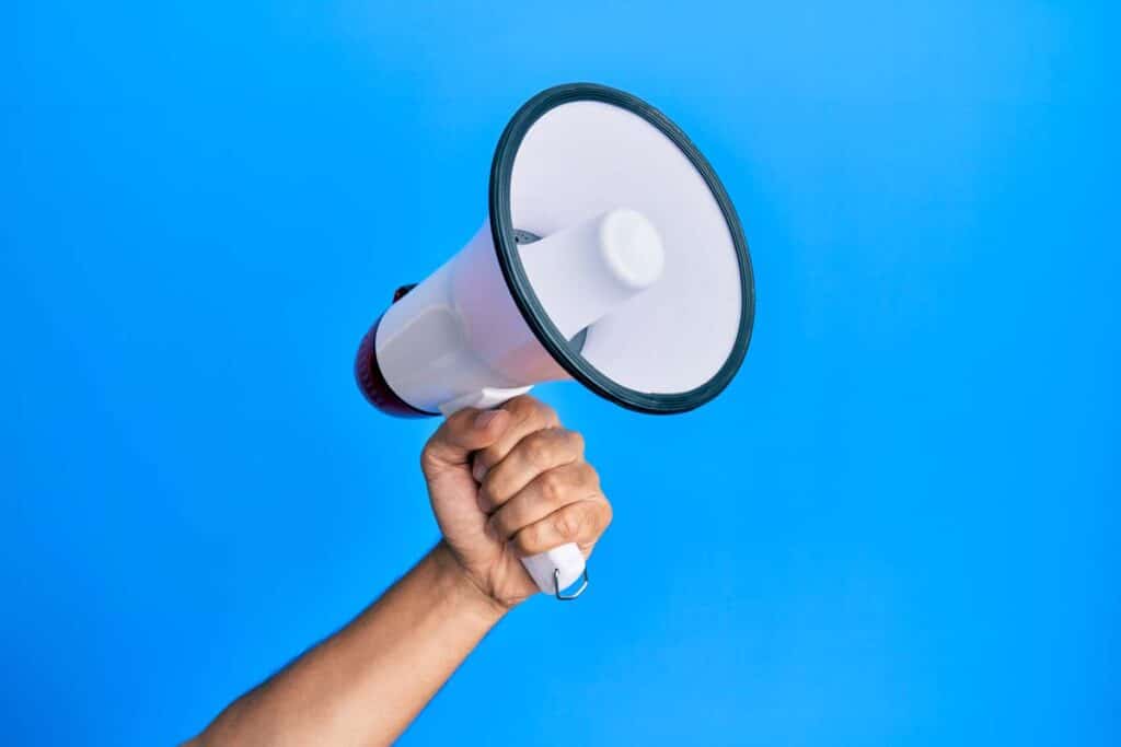 A hand holding a megaphone against a blue backdrop, representing top recalls for the week of Jan. 15.