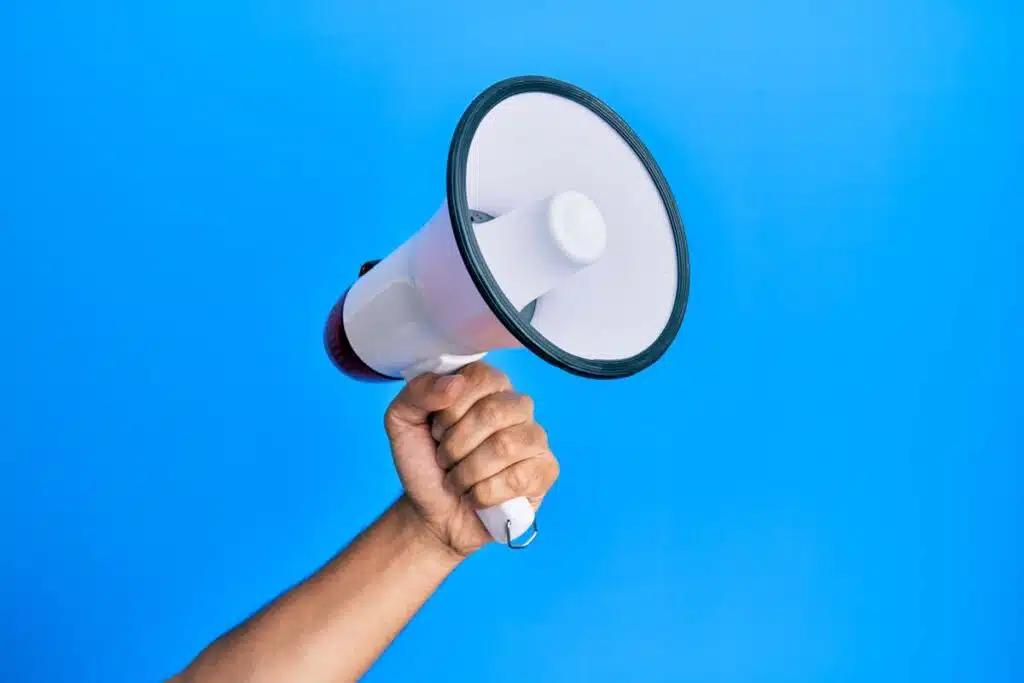 A hand holding a megaphone against a blue backdrop, representing top recalls for the week of Jan. 15.