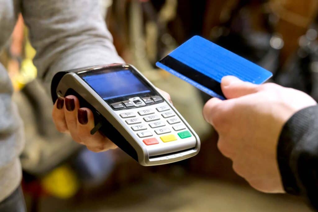 Close up of a card being used to make a payment, representing recent class actions over alleged hidden fees.