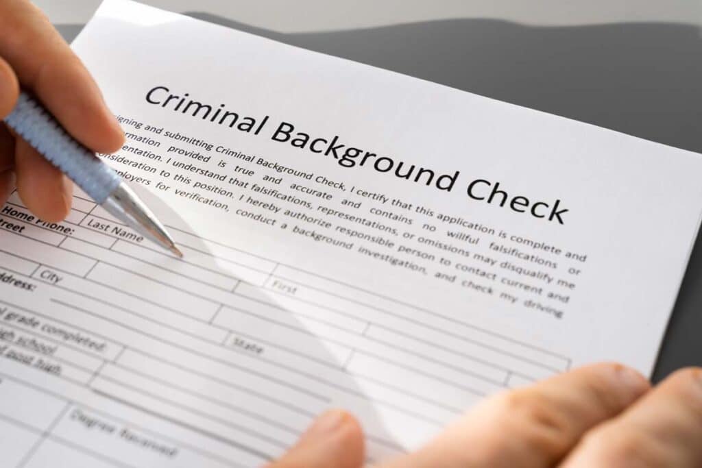 Hand holding a pen filling out a criminal background check document, representing the Accurate Background FCRA settlement.