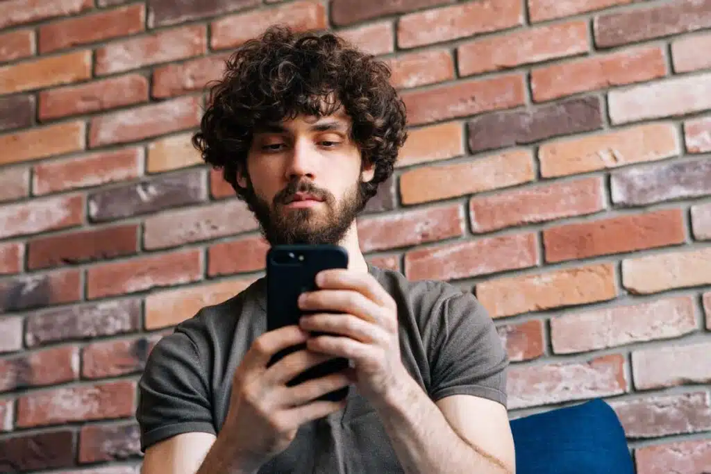 Close up of man reading a text message, representing the Ima Pizza class action settlement.