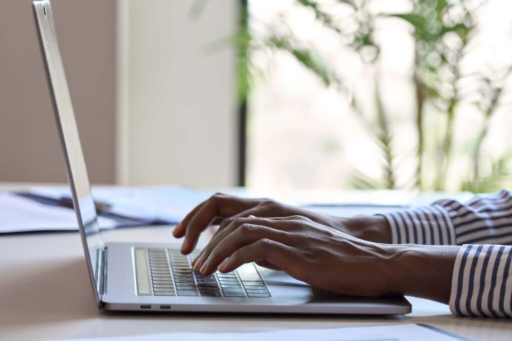 Close up of hands typing on a laptop, representing the National Debt Relief class action.
