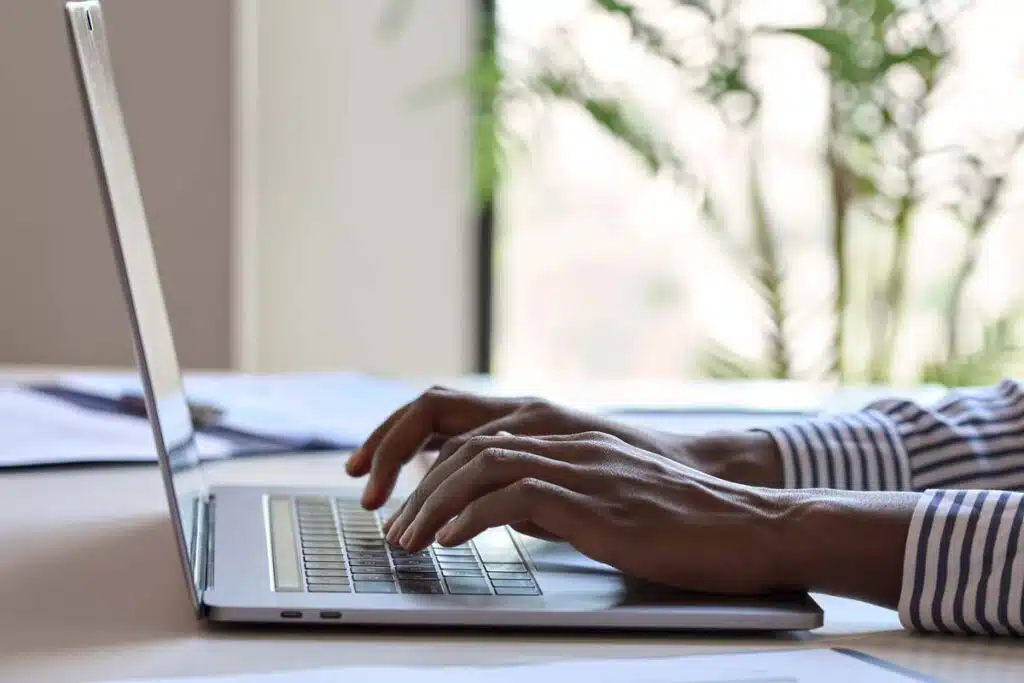 Close up of hands typing on a laptop, representing the National Debt Relief class action.