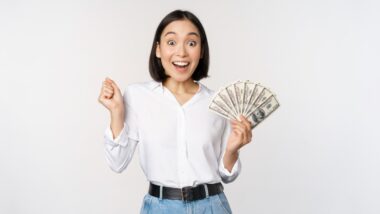 Happy woman with cash in hand, representing recent settlement payments to consumers.