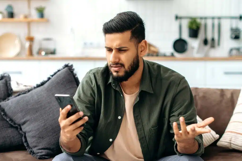 A confused male looking at a text on his phone, representing the Atlantic Recovery Solutions class action lawsuit settlement.